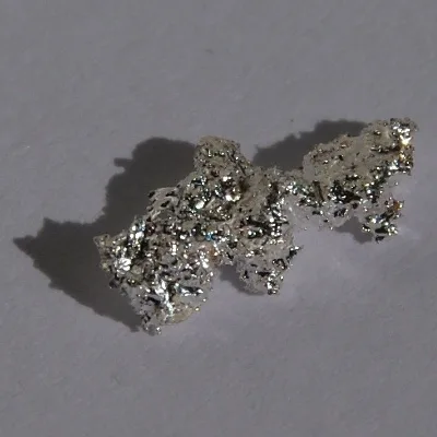 Silver nugget. Appearance depends on surface and storage conditions.